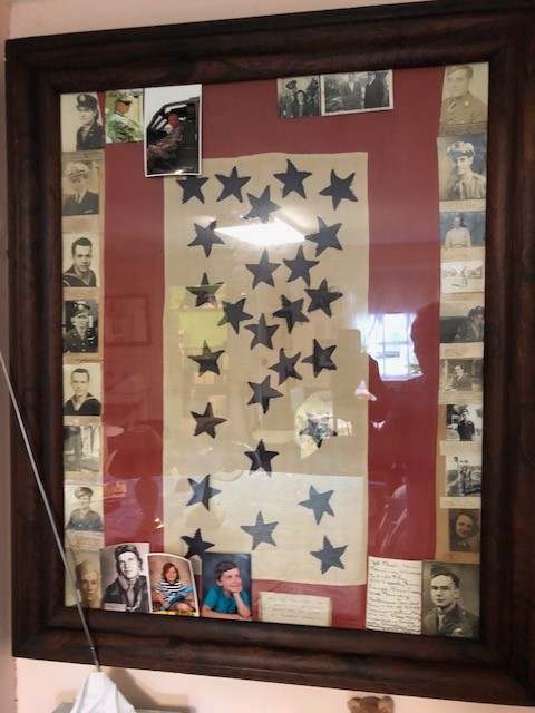 Framed World War II Blue Star Service Flag surrounded by family military portraits